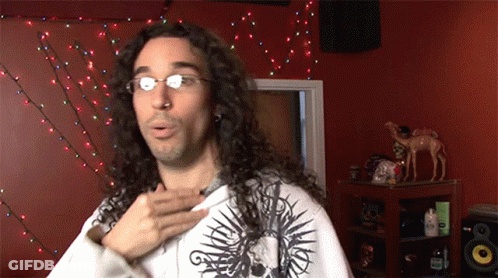 Man With Long Curly Hair And Glasses In Skull Shirt GIF