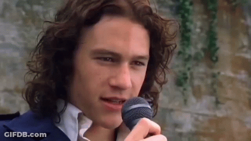 Man With Long Curly Hair Singing Into Microphone GIF
