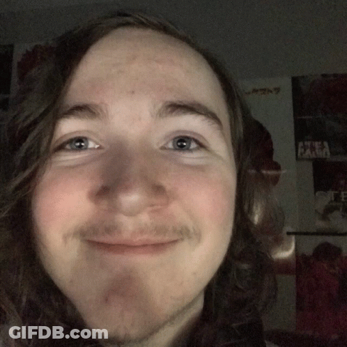 Man With Long Hair And Beard Smiling In Front Of Akira Poster GIF