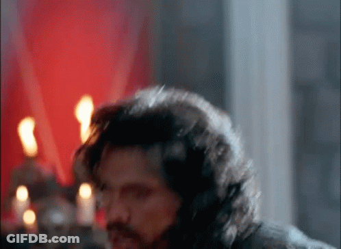 Man With Long Hair And Beard Standing In Candlelit Room GIF