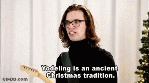 Man With Long Hair And Glasses Holding Guitar Says Yodeling Is An Ancient Christmas Tradition GIF