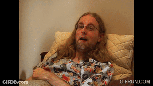 Man With Long Hair And Glasses Laying On Bed GIF