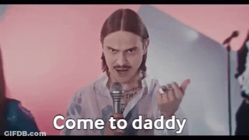 Man With Long Hair And Mustache Holding Microphone Saying Come To Daddy GIF