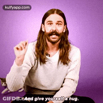 Man With Long Hair And Mustache Hugging Himself GIF