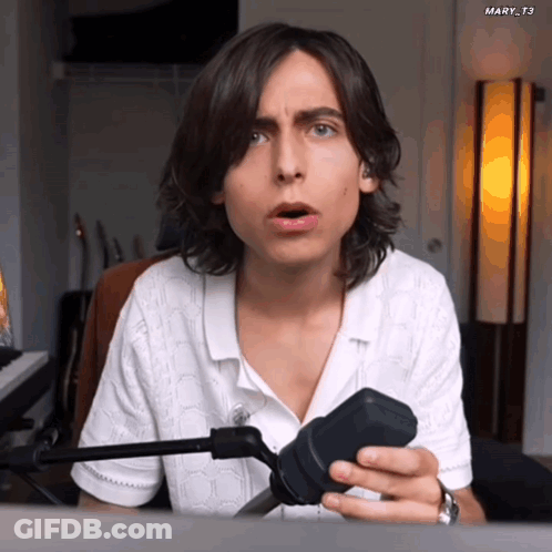 Man With Long Hair Holding Microphone Surprised GIF