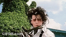 Man With Long Hair Holding Scissors GIF