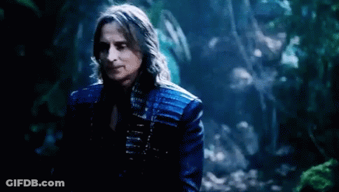 Man With Long Hair In Blue Jacket Standing In Woods GIF