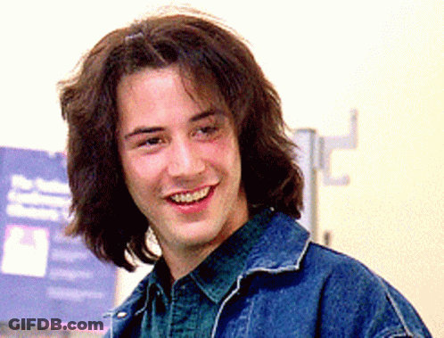 Man With Long Hair In Denim Jacket Smiles GIF