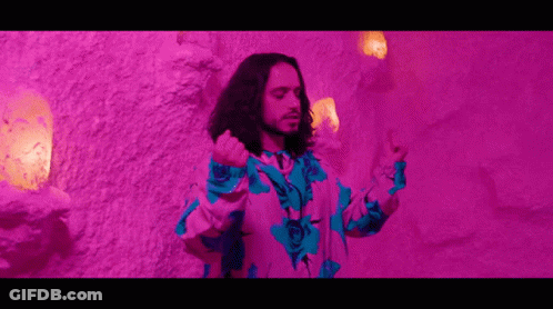 Man With Long Hair In Front Of Purple Wall GIF