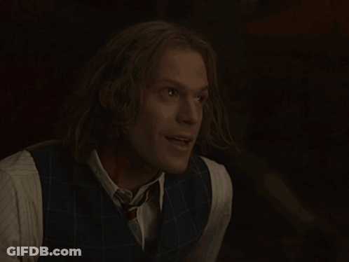 Man With Long Hair In Vest And Tie Smiles GIF