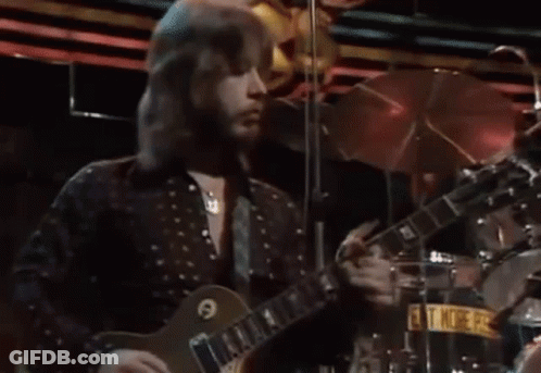 Man With Long Hair Playing Guitar On Stage GIF