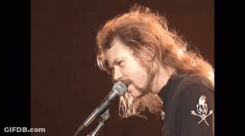 Man With Long Hair Singing Into Microphone GIF