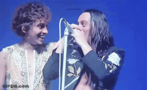 Man With Long Hair Singing Into Microphone GIF