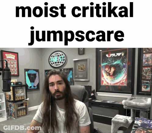 Man With Long Hair Sitting In Front Of Sign Saying Moist Critical Jumpscare GIF