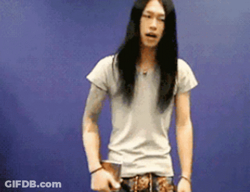 Man With Long Hair Standing In Front Of Blue Wall GIF