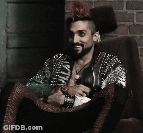 Man With Mohawk Sitting In Chair Wearing Wild Jacket GIF