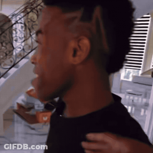 Man With Mohawk Standing By Window Blinds GIF