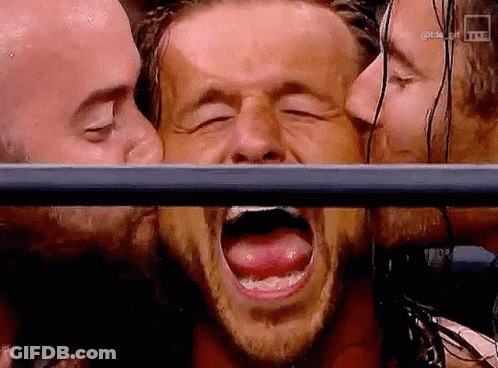 Man With Mouth Open Kissed By Two Men Behind Fence GIF