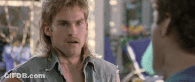 Man With Mullet Talking To Man In Denim Vest GIF