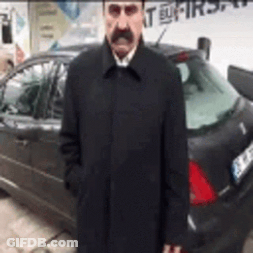 Man With Mustache And Coat Standing In Front Of Car GIF