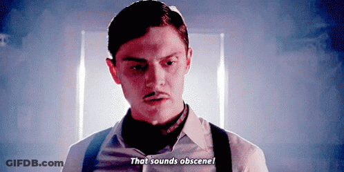 Man With Mustache And Suspenders Talking In Dark Room GIF