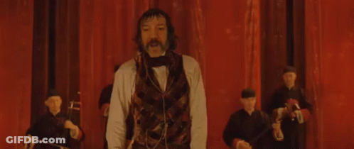 Man With Mustache Arms Outstretched On Stage GIF