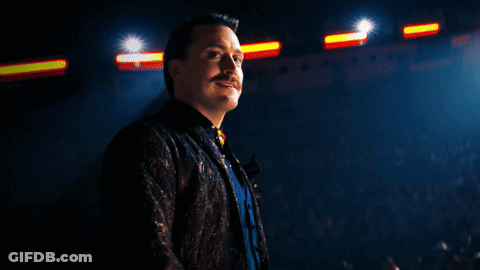 Man With Mustache In Front Of Crowd In Dark Room GIF