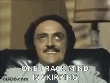 Man With Mustache Sitting In Chair Says One Track Mind Is Skipping GIF
