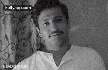 Man With Mustache Sitting In Front Of Curtain GIF