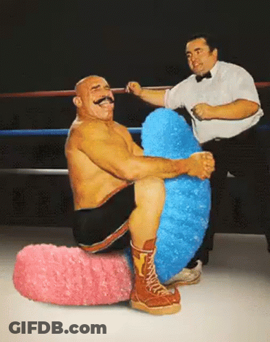 Man With Mustache Sitting On Pink And Blue Stuffed Animal GIF