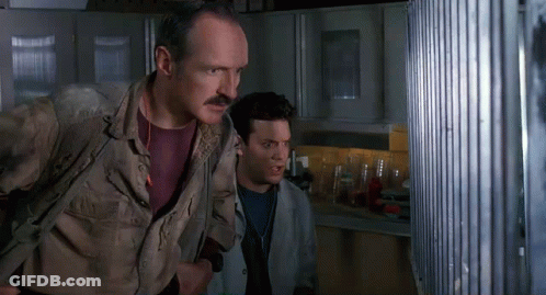 Man With Mustache Standing Beside Another Man Looking Out Window GIF