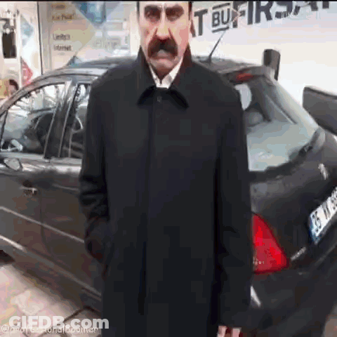Man With Mustache Standing In Front Of Black Car License Plate 35 TK 88 GIF