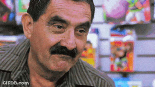 Man With Mustache Standing In Front Of Toy Wall GIF