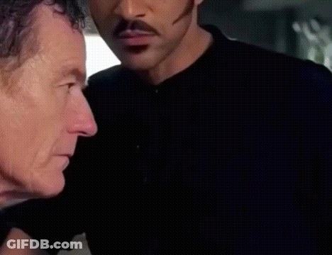 Man With Mustache Standing Next To Another Man In Dark Room GIF