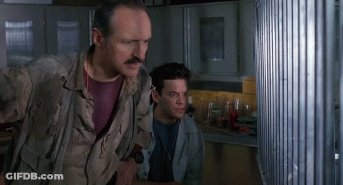 Man With Mustache Standing Next To Another Man Looking Out Window GIF