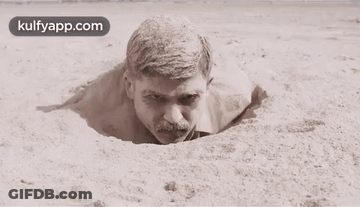 Man With Mustache Sticking Head Out Of Sand Hole GIF