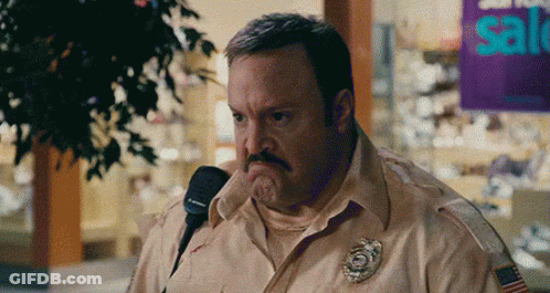 Man With Mustache Talking Into Microphone In Front Of Sale Sign GIF