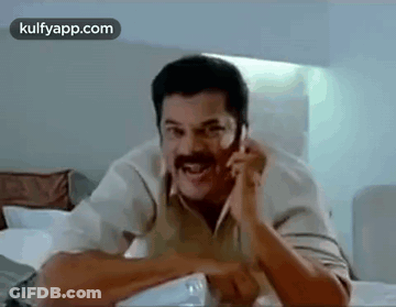 Man With Mustache Talking On Cell Phone In Bedroom GIF