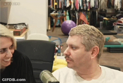 Man With Mustache Talking To Woman At Microphone GIF