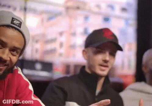 Man With Red Heart Hat Standing Next To Man GIF