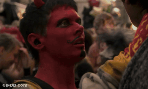 Man With Red Paint And Mustache Looks At Another Man GIF