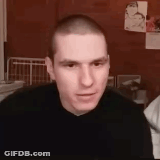 Man With Shaved Head In Black Sweater Looking At Camera GIF