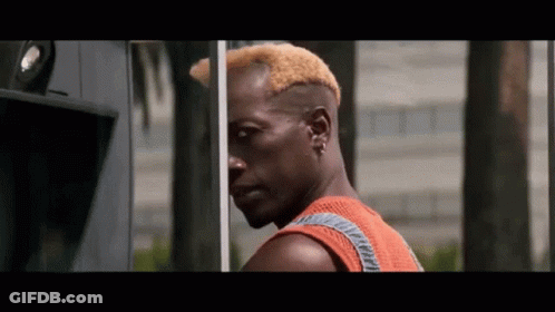 Man With Shaved Head Standing In Front Of Building GIF