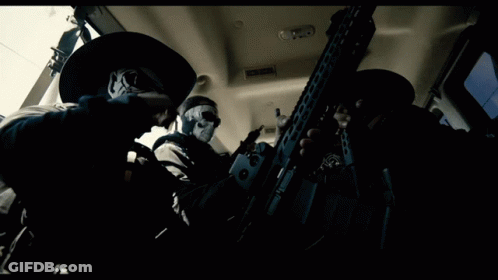 Man With Skull Mask Holding Gun In Dark Room GIF