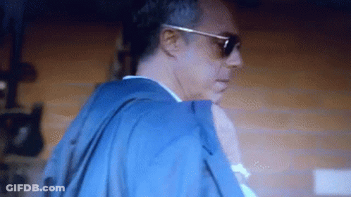 Man With Sunglasses And Blue Jacket In Dark Room GIF