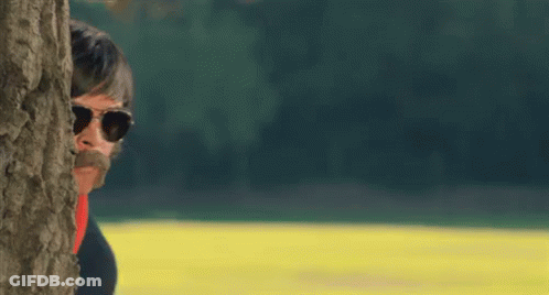 Man With Sunglasses And Mustache Behind Tree GIF