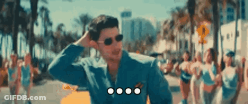 Man With Sunglasses In Blue Jacket Standing In Crowd GIF