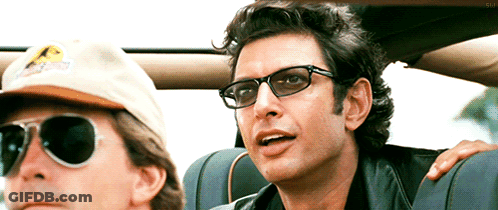 Man With Sunglasses Next To Man In Jurassic Park Hat GIF