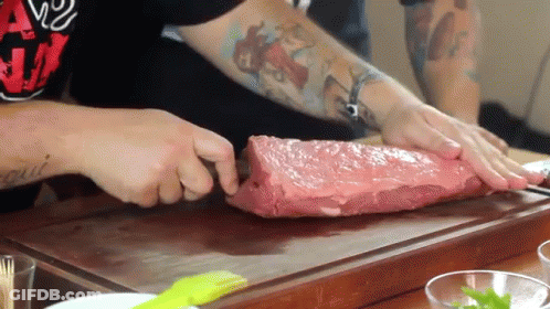 Man With Tattoo Cutting Large Piece Of Meat GIF