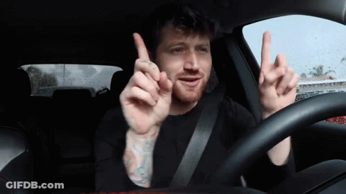 Man With Tattoo Driving Car Pointing Up GIF